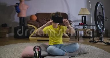 在虚拟现实中，一个笑着的白人男孩坐在地毯上移动他的身体。 快乐的小学生